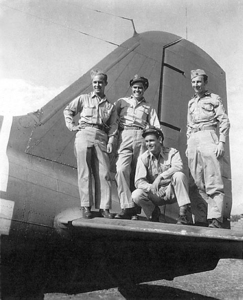 Four WWII airmen posing on airplane tail