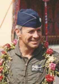 Smiling pilot in flight suit with garlands