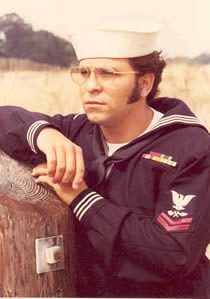 Sailor in navy uniform leaning on wooden fence