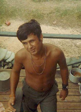 Shirtless man wearing necklaces on wooden deck