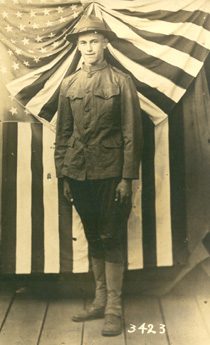 World War I soldier standing before American flag
