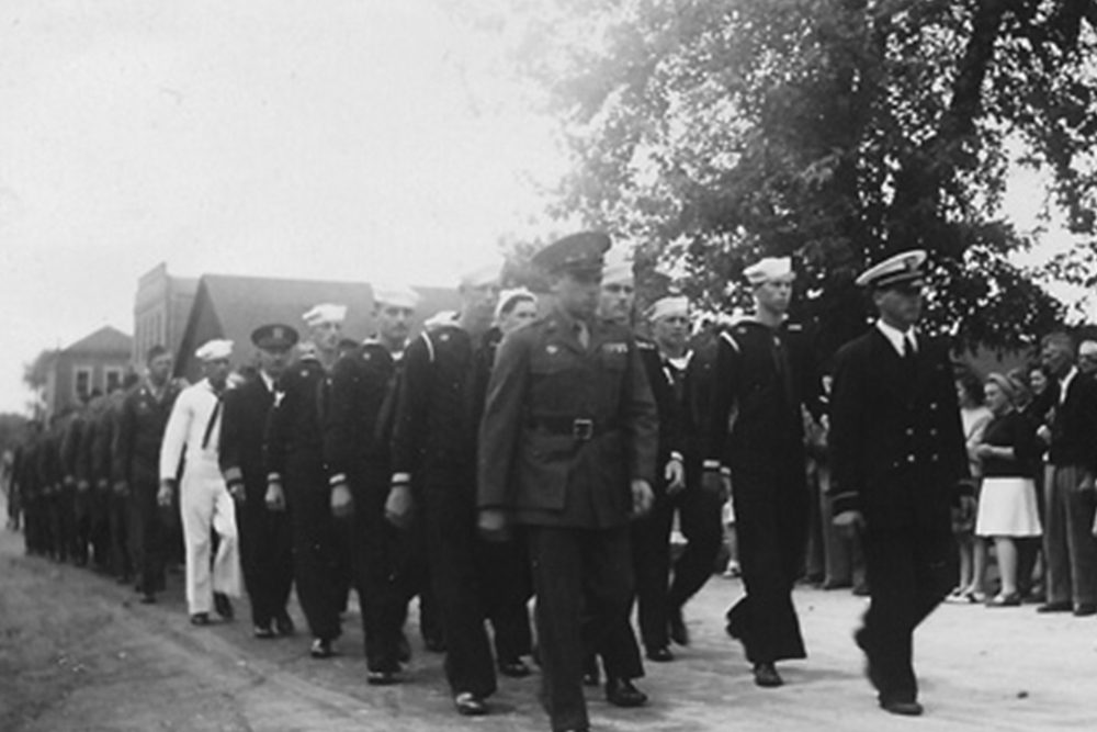Uniformed sailors with officer marching in formation