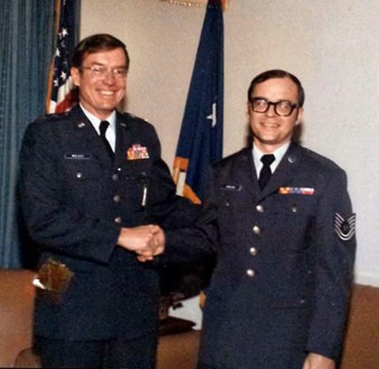 Two uniformed servicemen shaking hands, U.S. flags